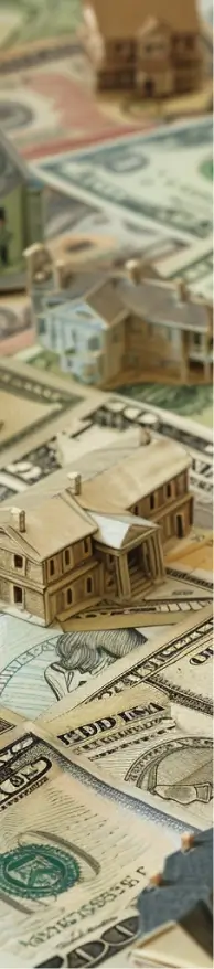 Birds-eye view of a neighborhood of houses built on top of a map of dollar bills